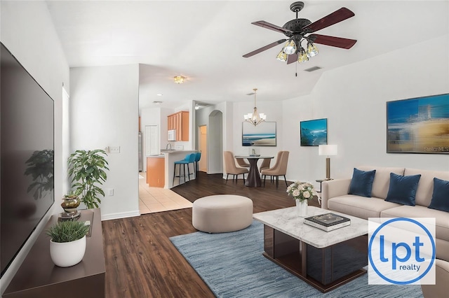 living room with ceiling fan with notable chandelier, dark hardwood / wood-style floors, and sink