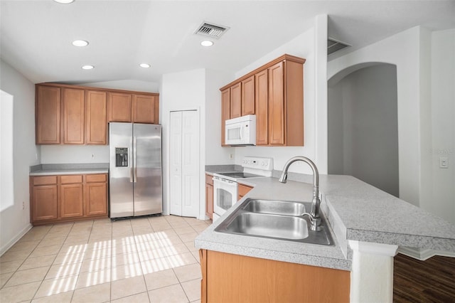 kitchen with light tile patterned flooring, white appliances, kitchen peninsula, and sink