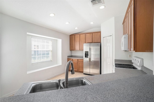 kitchen with light tile patterned floors, white appliances, vaulted ceiling, and sink