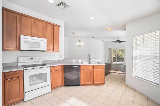 kitchen featuring white appliances, ceiling fan with notable chandelier, sink, hanging light fixtures, and light hardwood / wood-style floors