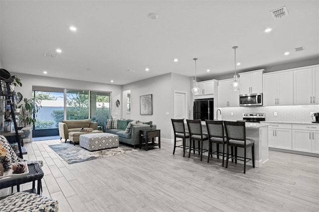 living room featuring sink and light hardwood / wood-style floors