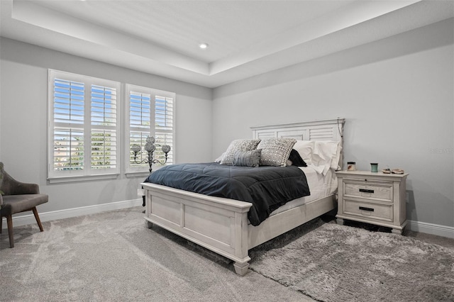 carpeted bedroom featuring a raised ceiling