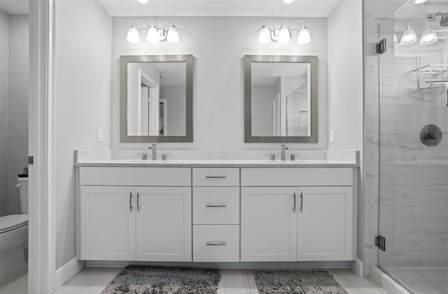 bathroom with vanity, toilet, and a shower with door