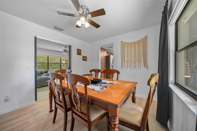 dining room featuring ceiling fan, light wood-type flooring, and a textured ceiling