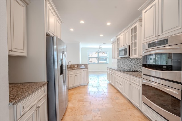 kitchen featuring white cabinets, sink, light stone countertops, tasteful backsplash, and stainless steel appliances