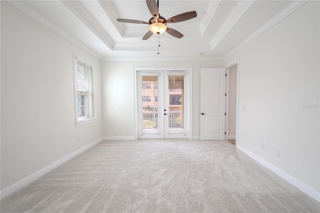 unfurnished room with a tray ceiling, ceiling fan, french doors, and light carpet