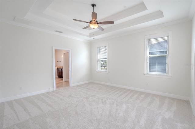 spare room with light colored carpet, ceiling fan, a raised ceiling, and ornamental molding