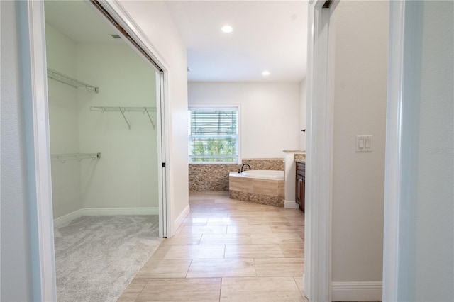 bathroom featuring tile patterned floors, a relaxing tiled tub, and vanity