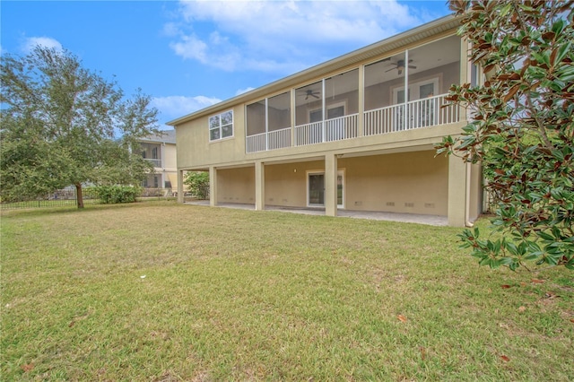 back of property featuring ceiling fan and a yard