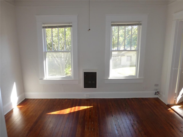 spare room with plenty of natural light, dark wood-type flooring, and heating unit