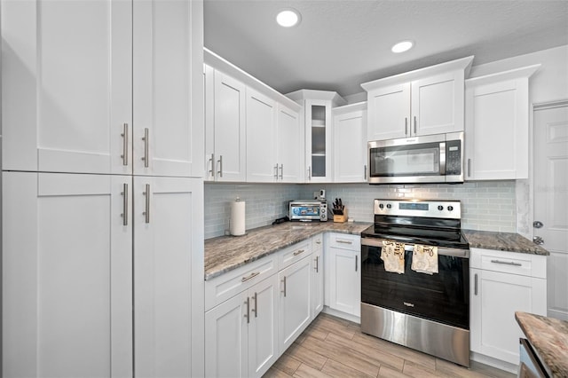 kitchen featuring light stone countertops, appliances with stainless steel finishes, light hardwood / wood-style flooring, and white cabinetry