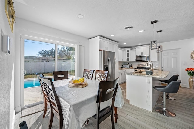 dining area with light hardwood / wood-style flooring, a textured ceiling, and sink