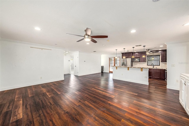 unfurnished living room featuring sink, dark wood-type flooring, and ornamental molding