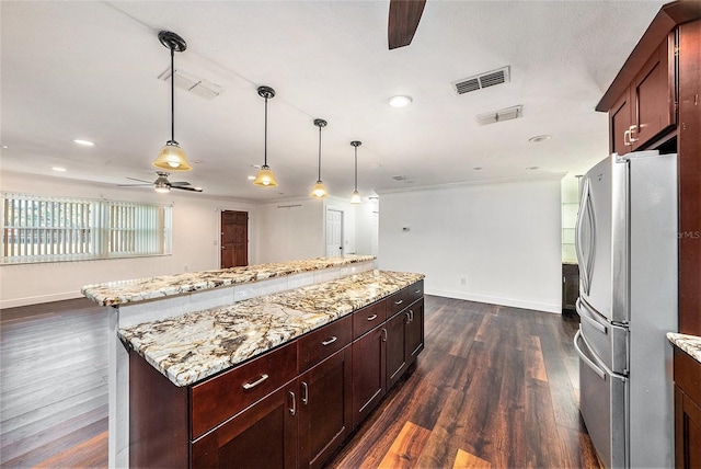 kitchen featuring ceiling fan, light stone countertops, dark hardwood / wood-style floors, stainless steel fridge, and decorative light fixtures