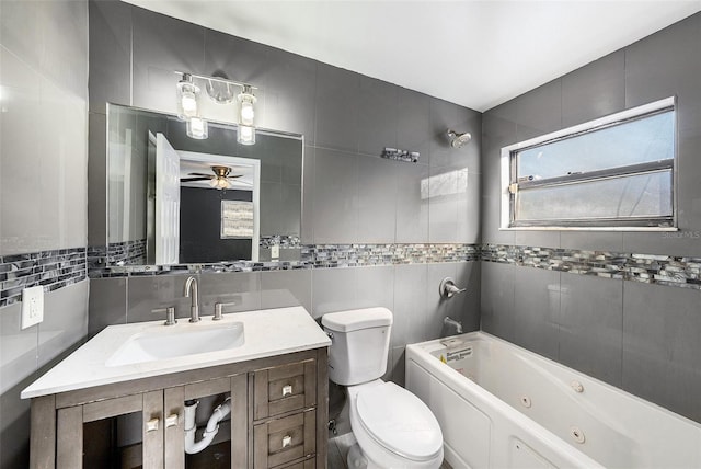 full bathroom featuring ceiling fan, sink, washtub / shower combination, toilet, and tile walls