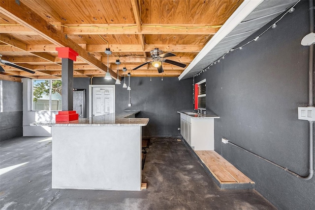 kitchen with stone countertops, ceiling fan, white cabinetry, and sink