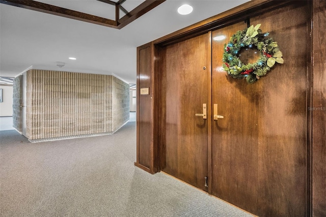 hallway featuring carpet flooring, lofted ceiling, and wooden walls