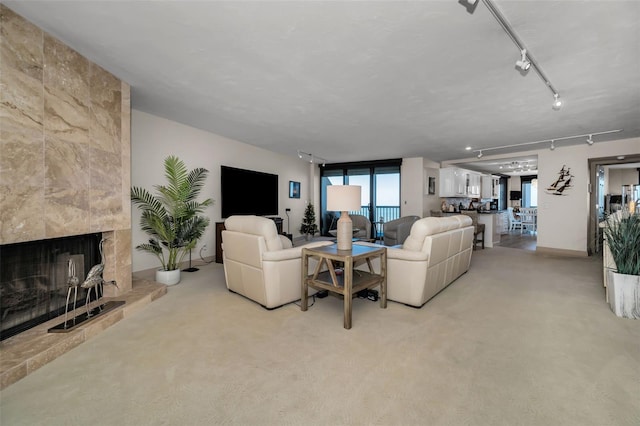 living room with light carpet, a large fireplace, and rail lighting