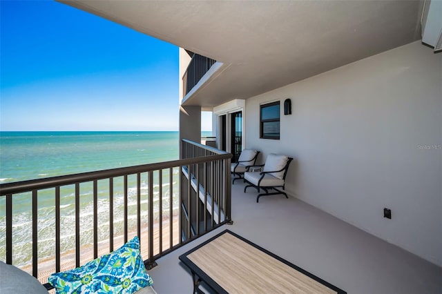 balcony with a water view and a view of the beach