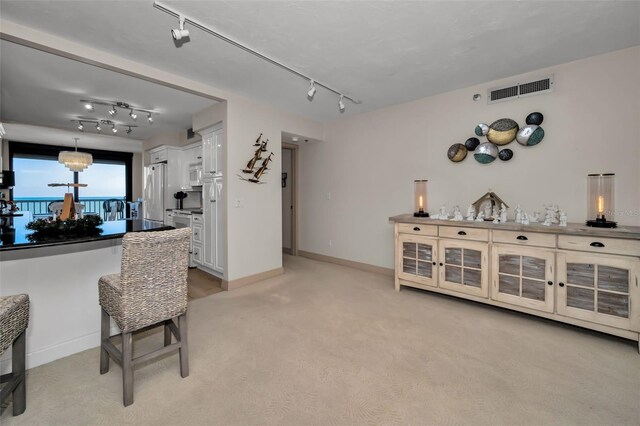 bar with pendant lighting, white appliances, light carpet, an inviting chandelier, and white cabinetry