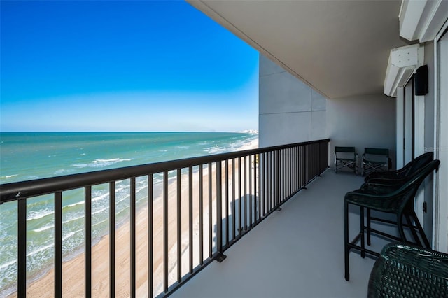 balcony with a water view and a view of the beach