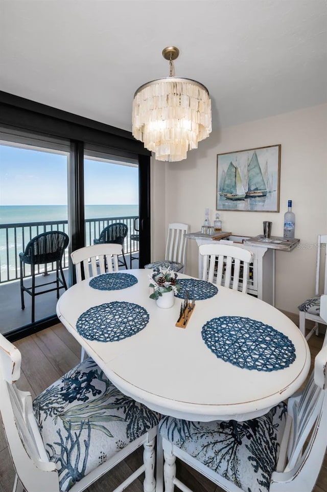 dining space with a water view, dark wood-type flooring, and a notable chandelier