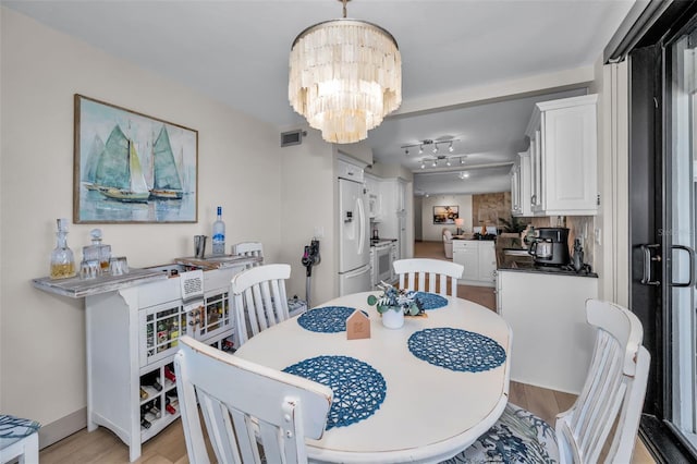 dining space with light hardwood / wood-style flooring and an inviting chandelier