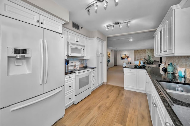 kitchen with white appliances, white cabinets, sink, light hardwood / wood-style flooring, and decorative backsplash