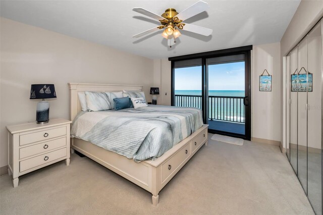 bedroom featuring access to exterior, light carpet, a water view, and ceiling fan