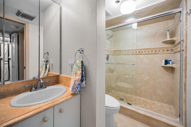 bathroom with vanity, toilet, and a shower with door