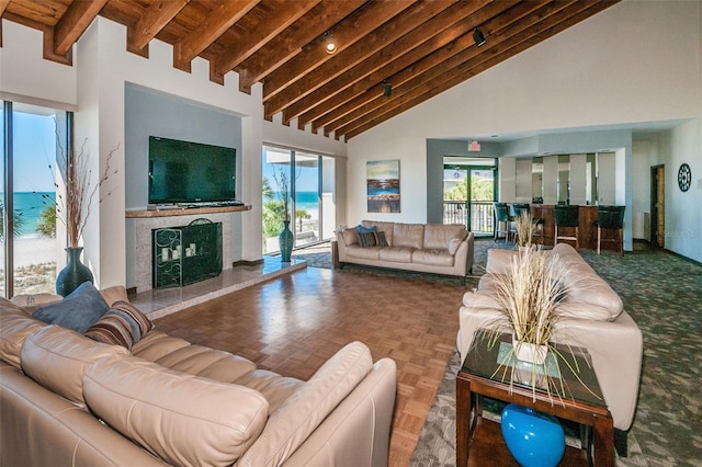 living room with beam ceiling, a tile fireplace, high vaulted ceiling, parquet flooring, and a water view