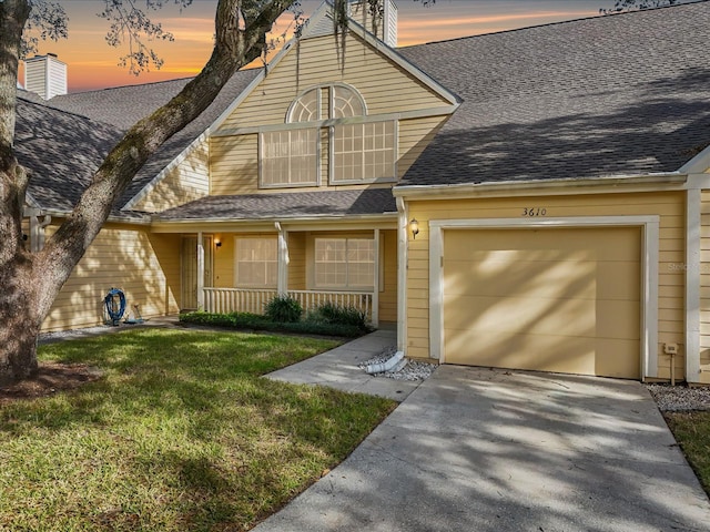 view of front of property with a yard, a porch, and a garage