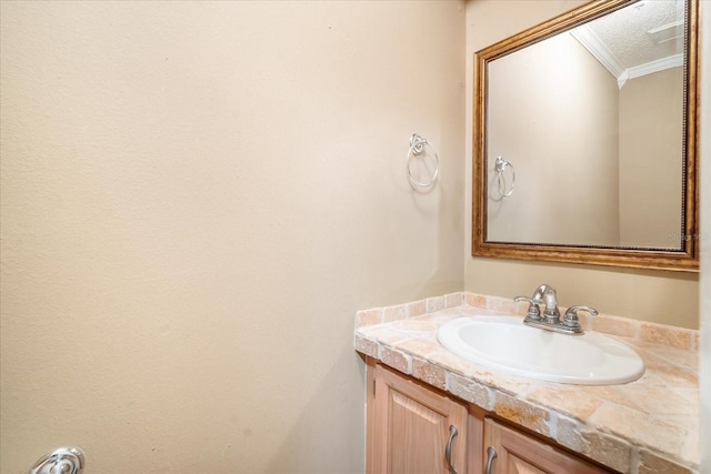 bathroom with a textured ceiling, vanity, and crown molding