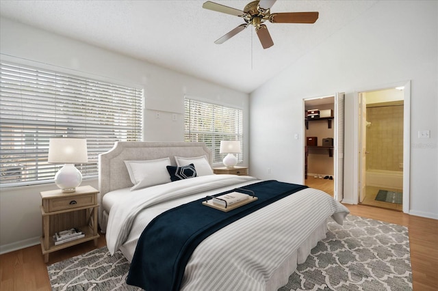 bedroom featuring high vaulted ceiling, hardwood / wood-style flooring, ensuite bath, and ceiling fan