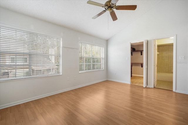 unfurnished bedroom with light wood-type flooring, ceiling fan, a spacious closet, connected bathroom, and lofted ceiling