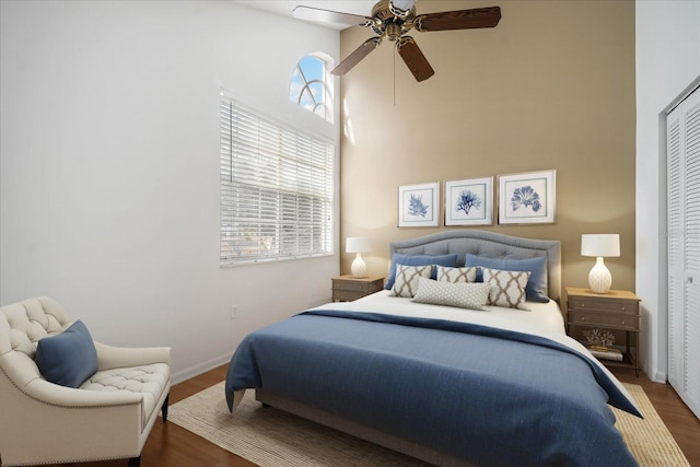 bedroom with multiple windows, ceiling fan, a closet, and dark hardwood / wood-style floors