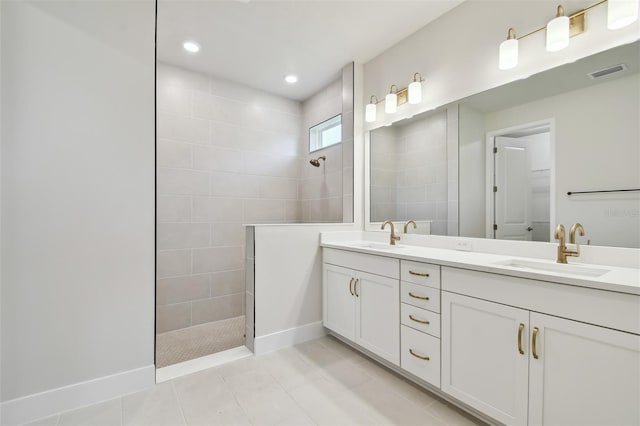 bathroom featuring tile patterned flooring, vanity, and a tile shower