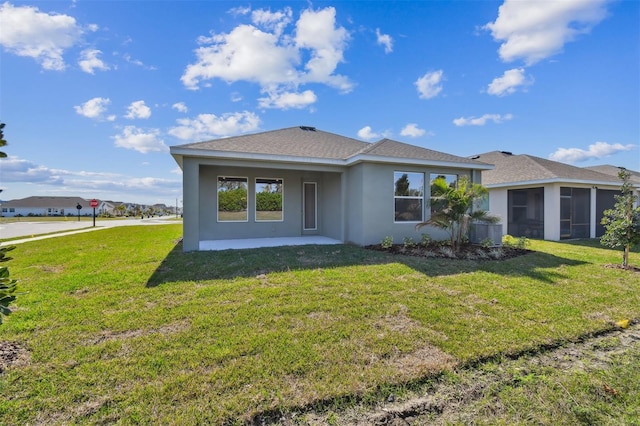 rear view of property featuring a yard, a patio, and a sunroom