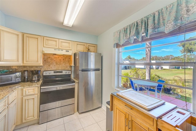 kitchen with light stone countertops, light tile patterned floors, backsplash, and stainless steel appliances