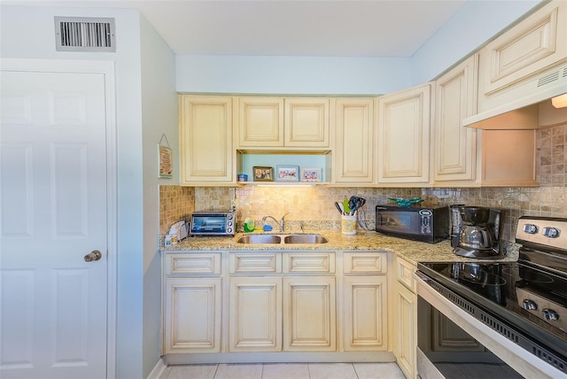 kitchen featuring sink, backsplash, premium range hood, light tile patterned flooring, and black appliances