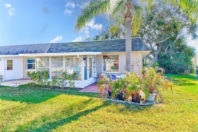 view of front of house with a front lawn, cooling unit, and a sunroom