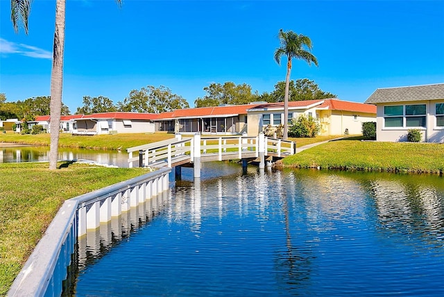 rear view of house with a water view and a lawn