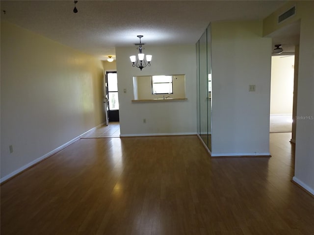 unfurnished room with a notable chandelier, wood-type flooring, and a textured ceiling