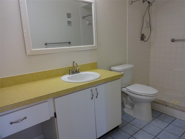 bathroom featuring tile patterned floors, vanity, a tile shower, and toilet