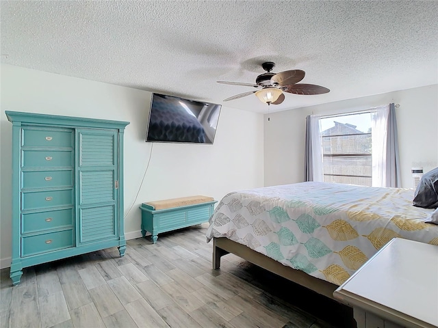 bedroom featuring ceiling fan, a textured ceiling, and light wood-type flooring