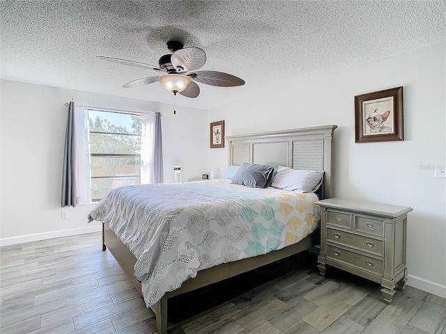 bedroom with ceiling fan, a textured ceiling, and hardwood / wood-style flooring