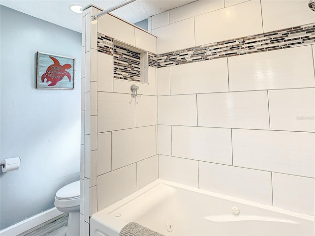 bathroom with hardwood / wood-style flooring, tiled shower / bath combo, and toilet