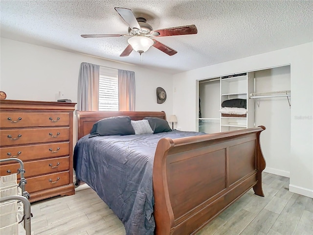 bedroom with a textured ceiling, light hardwood / wood-style flooring, a closet, and ceiling fan