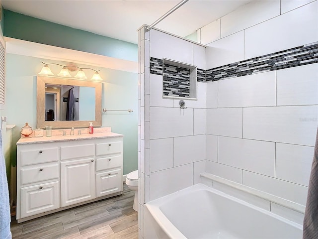 full bathroom featuring vanity, tiled shower / bath combo, hardwood / wood-style flooring, and toilet