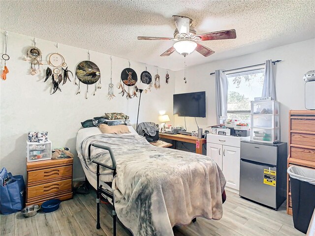 bedroom with a textured ceiling, light wood-type flooring, and ceiling fan